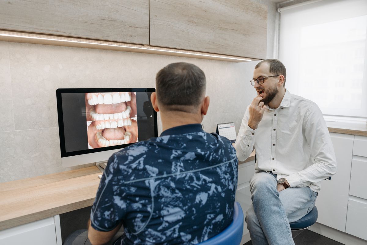 Dentista mostrando a un paciente su plan de tratamiento en pantalla.